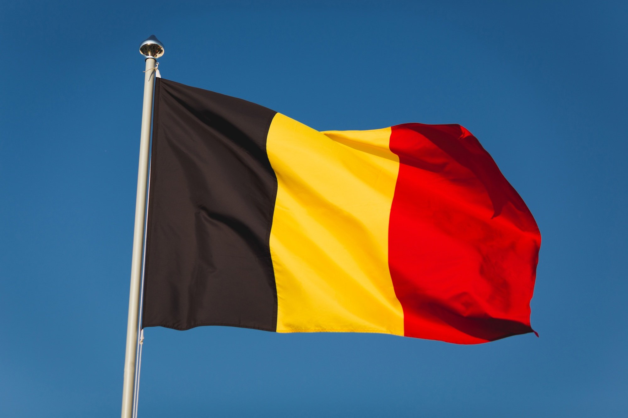 Flag of Belgium on mast. National flag against wind blue sky
